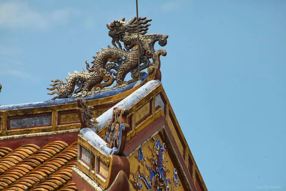 Detailed dragon sculpture on a traditional roof in Hue City, showcasing Vietnamese architecture.
