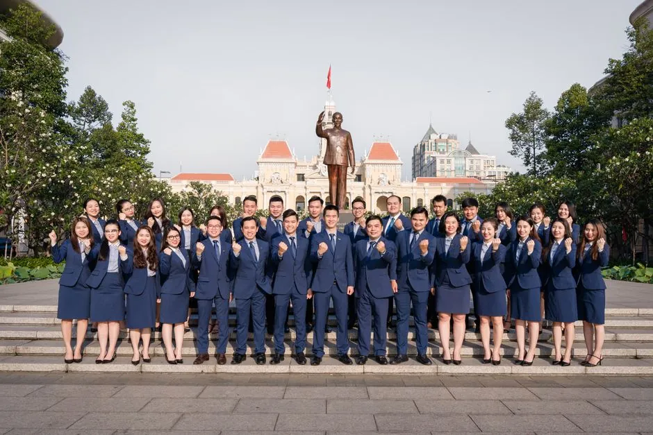 Business professionals posing confidently in front of the Ho Chi Minh statue, Vietnam.