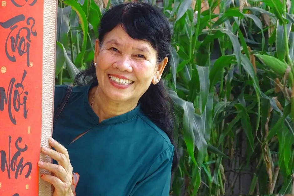 Happy elderly woman holding a traditional scroll in a garden setting.