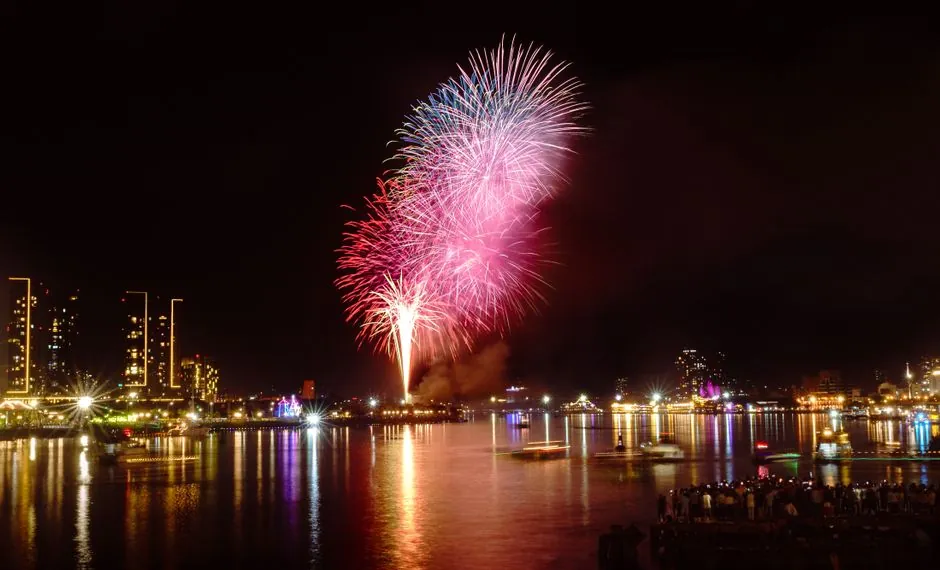 Dazzling fireworks light up the night sky in Ho Chi Minh City, Vietnam, reflecting on the Saigon River.