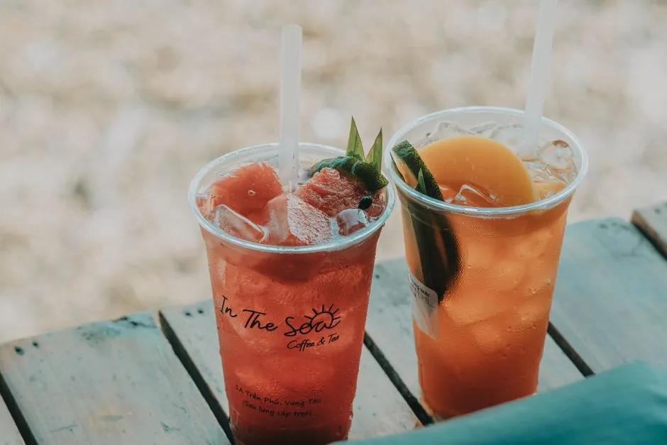Two iced summer drinks on a wooden table, perfect for outdoor refreshment.
