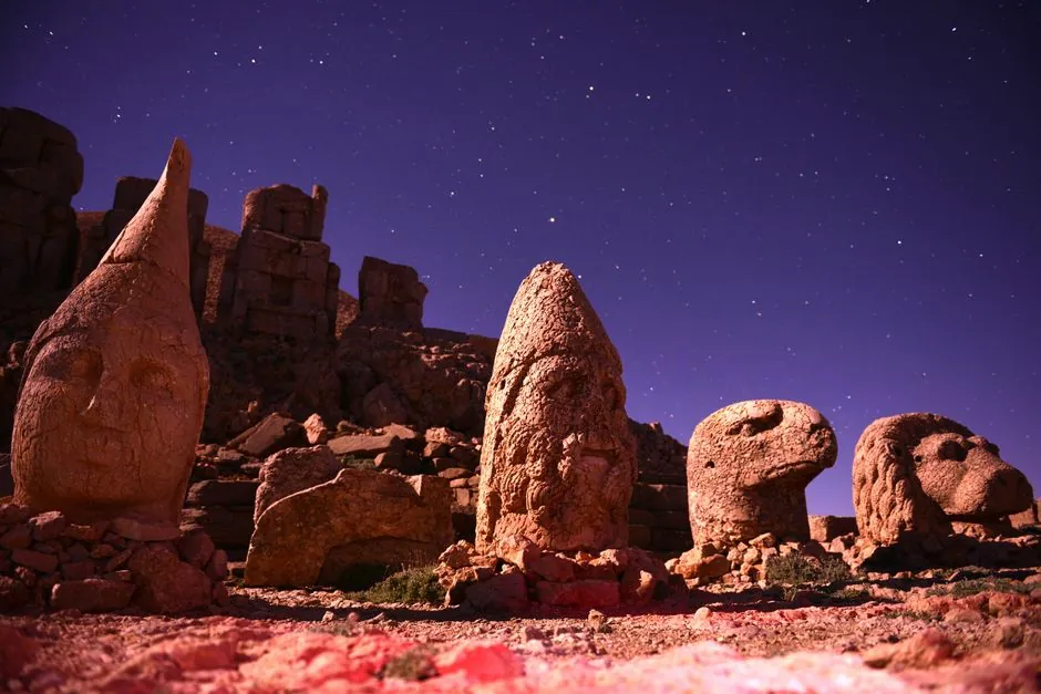 Nighttime view of the colossal stone heads at Mount Nemrut, Turkey, under a starry sky.