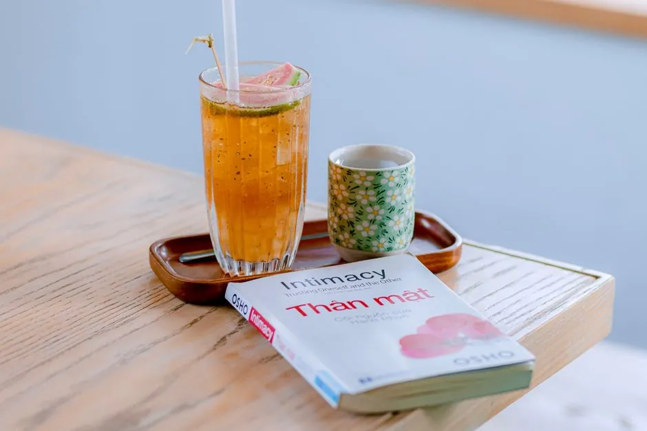 Glass of iced tea and book on a wooden table, providing a cozy reading setup indoors.